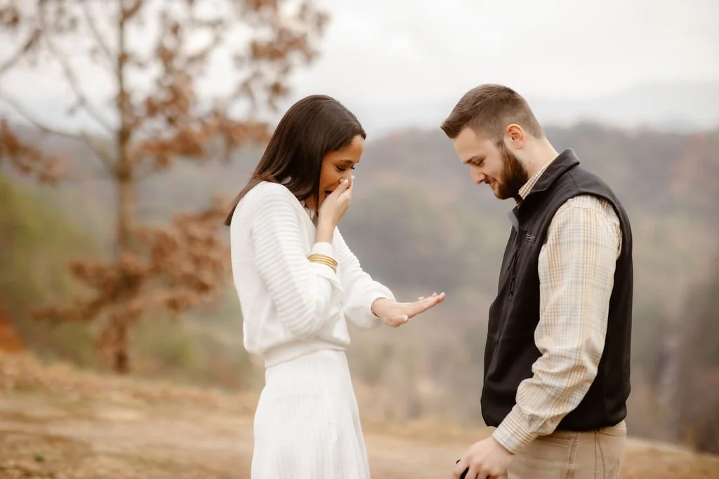 Woman covering her mouth in surprise while admiring engagement ring at mountain overlook, Gatlinburg photographer capturing candid proposal reaction with engagement photos clothes inspiration in a fall Smoky Mountains setting
