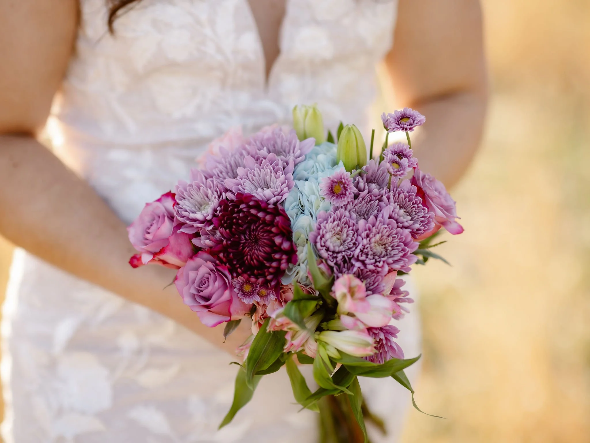 Close-up of a colorful bridal bouquet with pink, purple, and blue flowers held by a bride during wedding traditions while eloping to Gatlinburg with a Gatlinburg photographer.