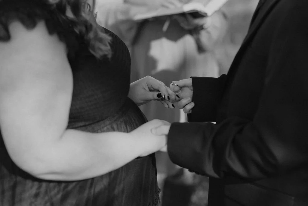 Black and white close-up of couple holding hands during Halloween Wedding ceremony, intimate vow exchange moment captured by Gatlinburg photographer with moody, romantic elopement details
