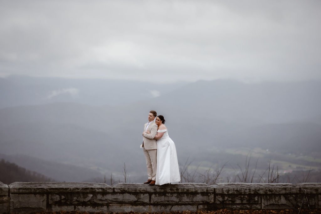 Newlyweds embracing on a scenic mountain overlook with panoramic views during a foothills elopement, photographed by a gatlinburg photographer.