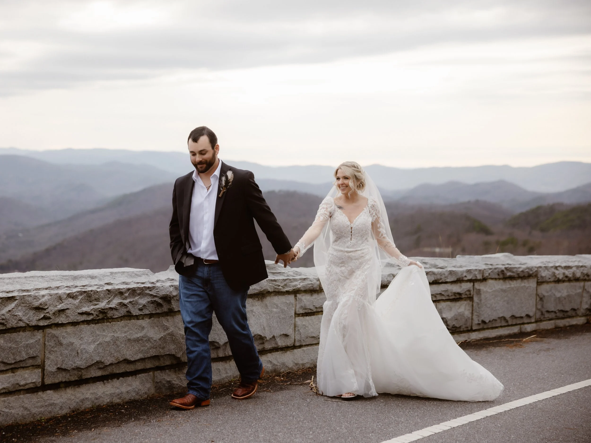Bride and groom walking hand in hand along a mountain overlook during a Smoky Mountain elopement, captured by a Gatlinburg photographer with scenic Appalachian views in the background.