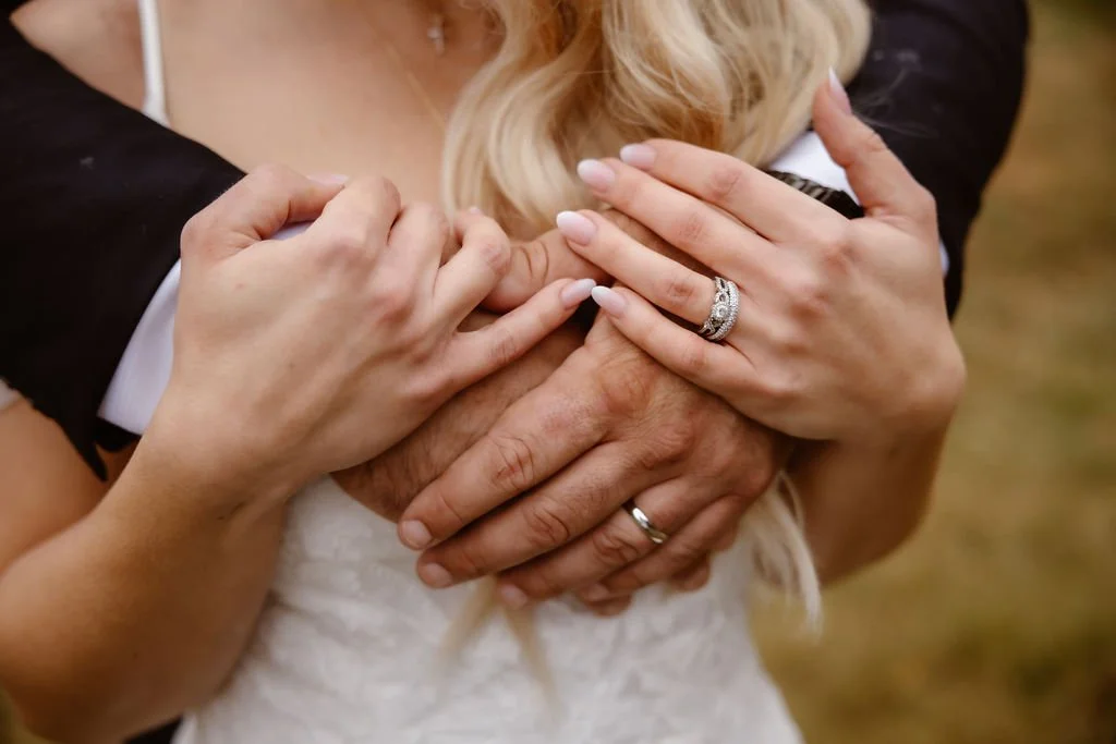 Close-up of the couple’s intertwined hands, highlighting their wedding rings and the bride’s delicate lace gown—an intimate detail from their Foothills Parkway micro wedding in the Smoky Mountains.