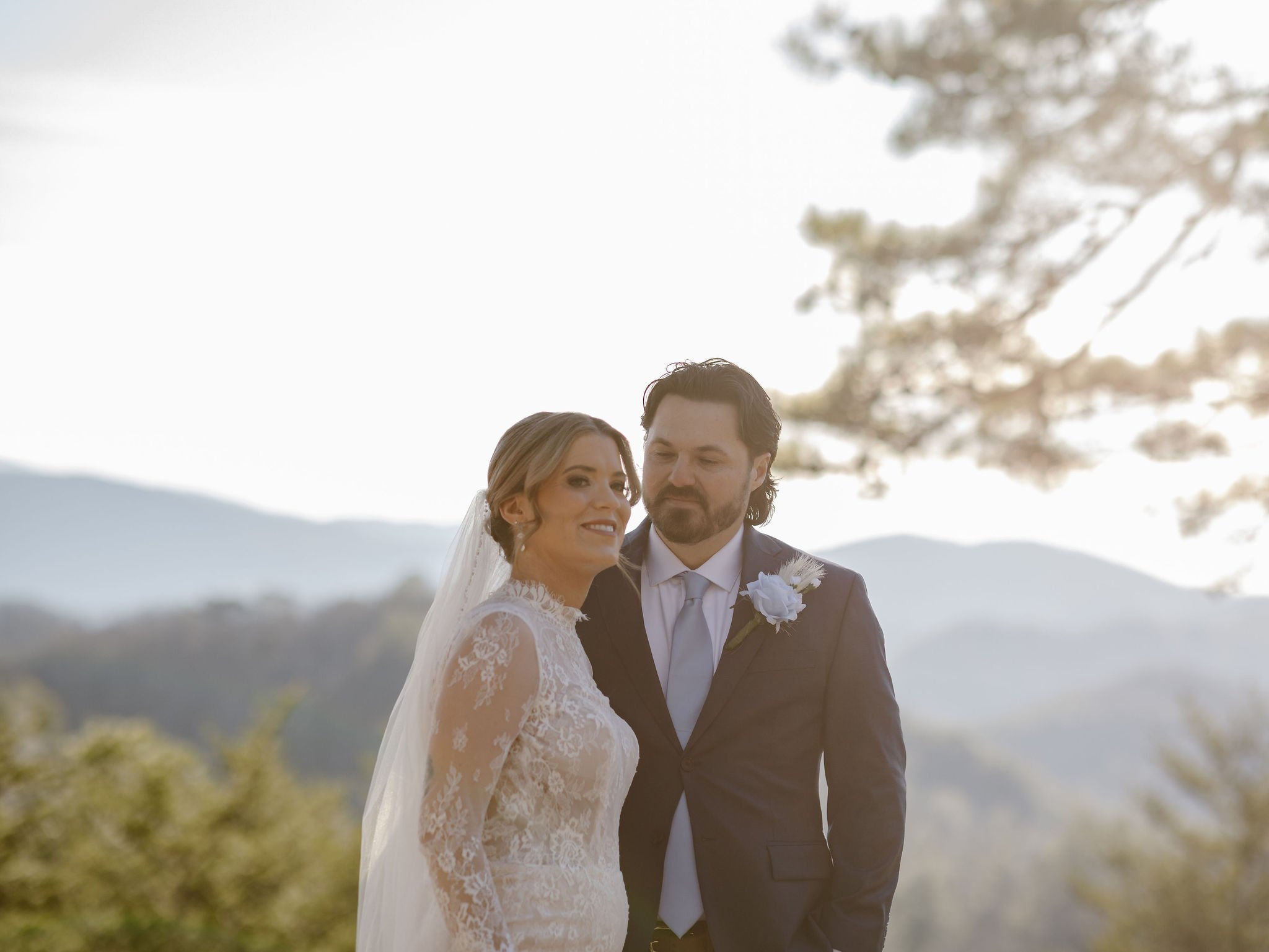 Bride and groom standing closely together with a hazy mountain backdrop at Foothills Parkway, captured in soft natural light by National Park Photographers in the Smoky Mountains.
