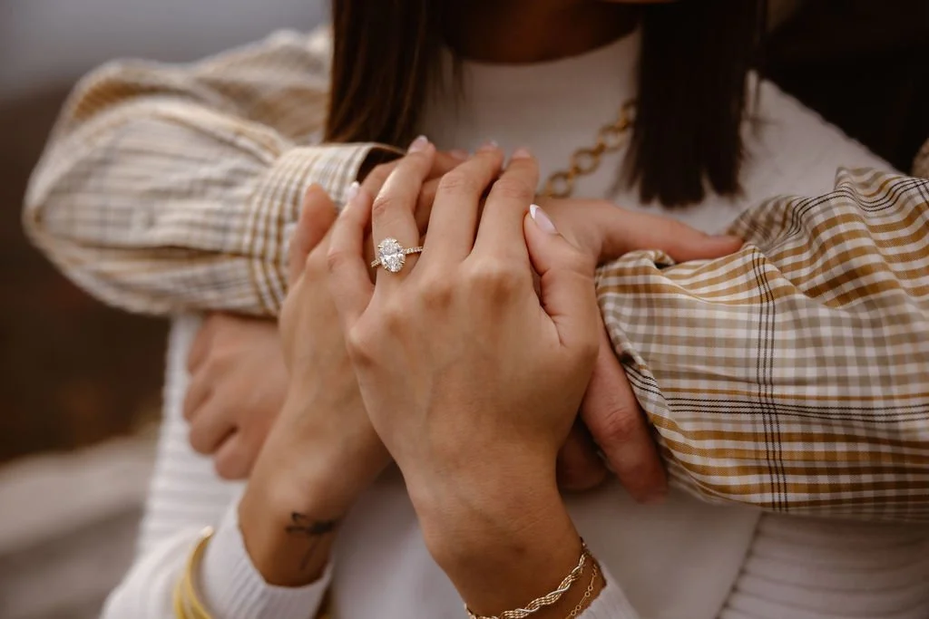 Close-up of couple embracing with oval diamond engagement ring in focus, highlighting engagement photos clothes details captured by Gatlinburg photographer at Foothills Parkway