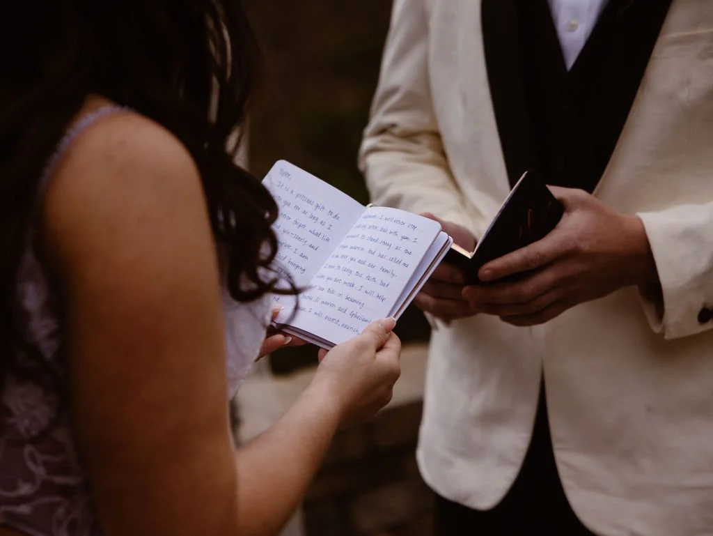 Bride and groom read handwritten vows during an intimate ceremony at Gatlinburg wedding cabins, with an elopement photographer capturing the personal exchange against a mountain backdrop.