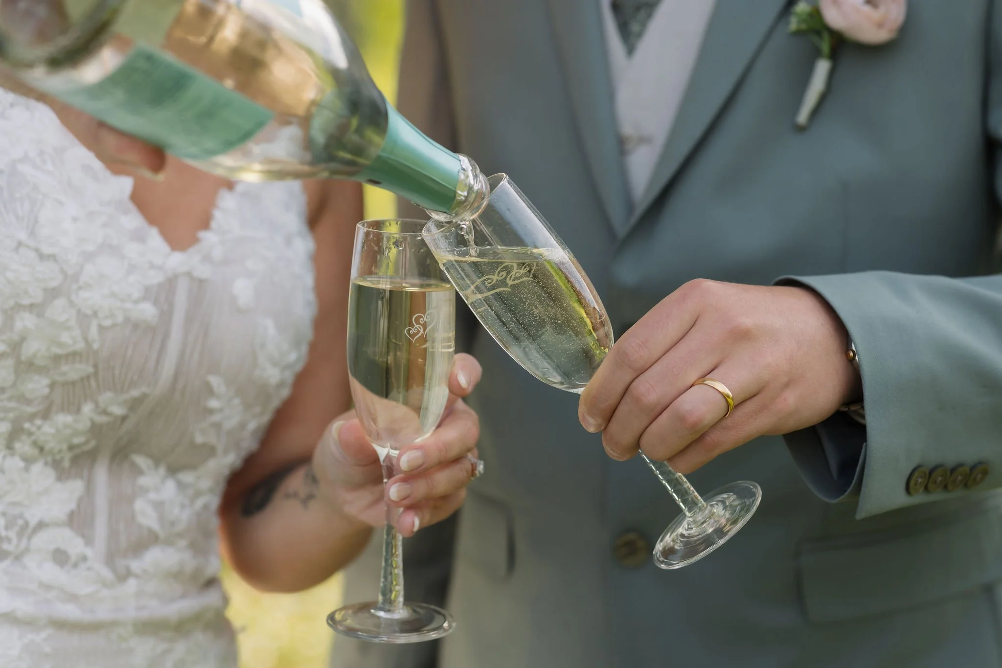 Close-up of newlyweds pouring champagne into engraved glasses, a celebratory detail captured by their Gatlinburg wedding photographer.
