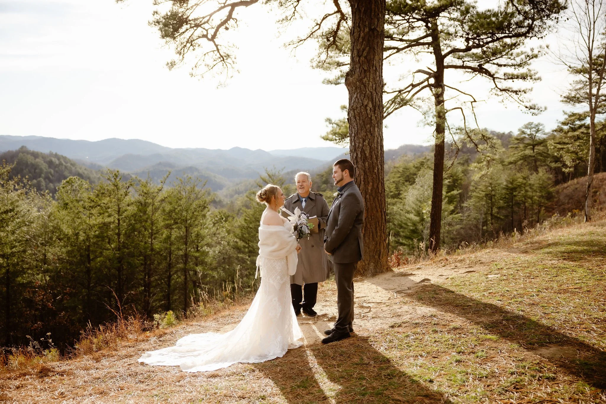 Outdoor mountain wedding ceremony with bride and groom exchanging vows beside an officiant in the Smoky Mountains, photographed during a Gatlinburg wedding by a Gatlinburg wedding photographer.
