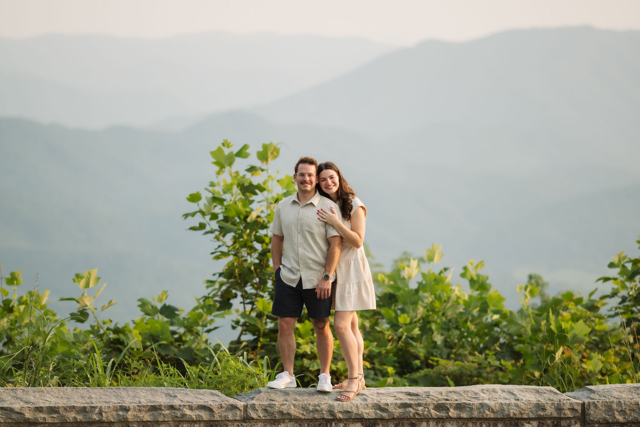 Couple posing with panoramic mountain views during their smoky mountain engagement session, photographed at golden hour by a Gatlinburg photographer.