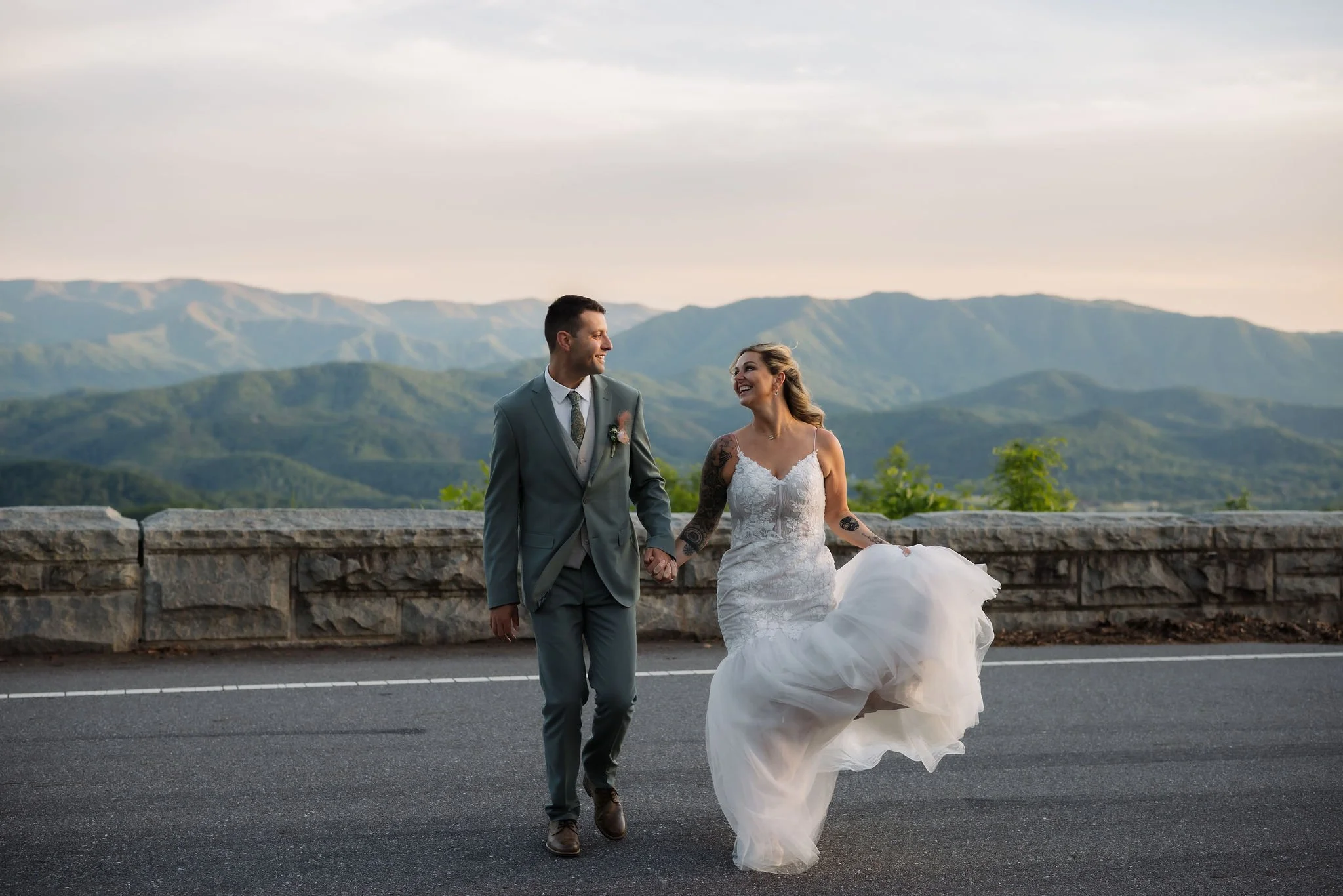 Newlyweds walk hand in hand along Foothills Parkway with sweeping Smoky Mountain views after their Gatlinburg elopement ceremony.