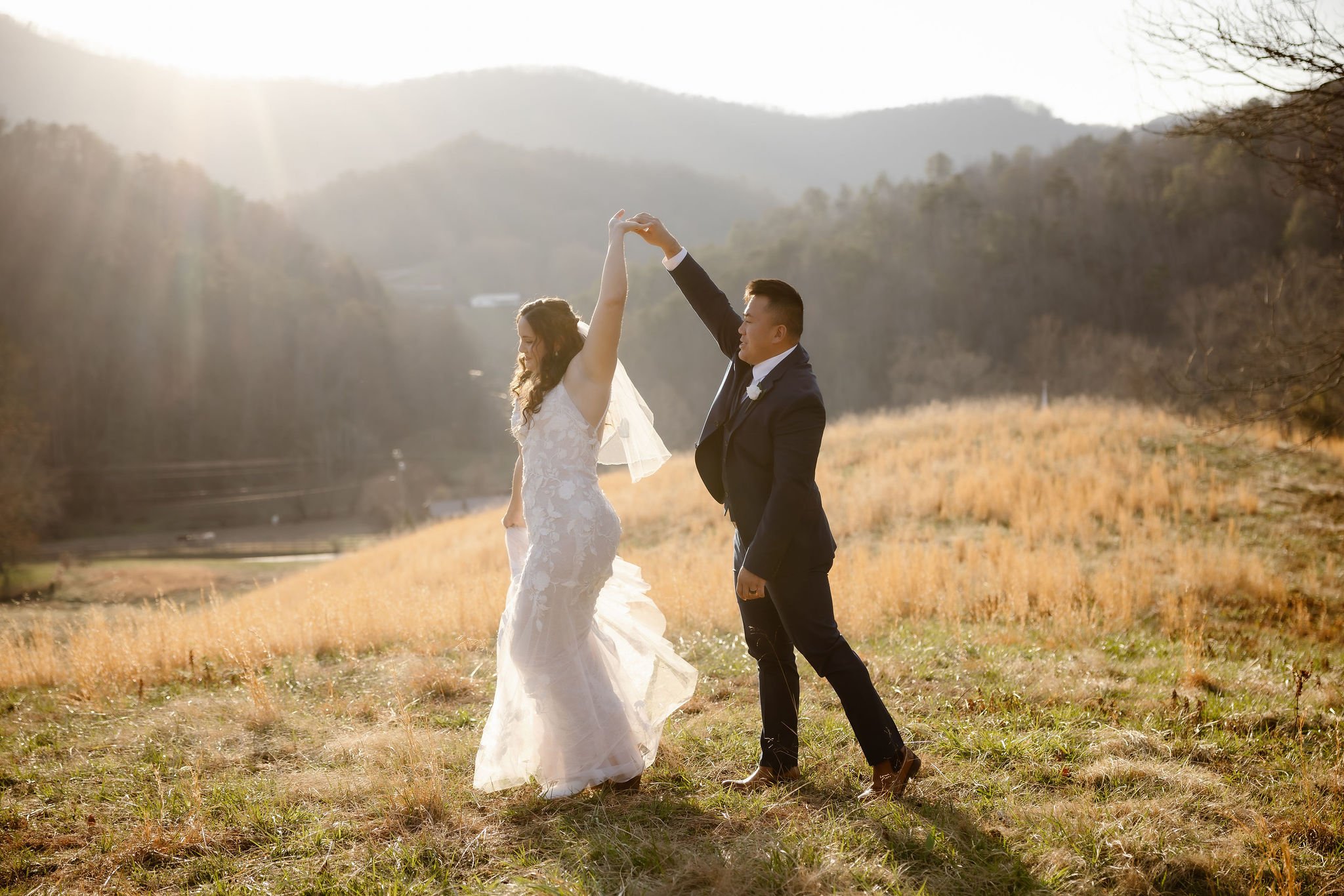 Bride and groom dancing together in a golden mountain field at sunset, capturing joyful wedding traditions while eloping to Gatlinburg with a Gatlinburg photographer.