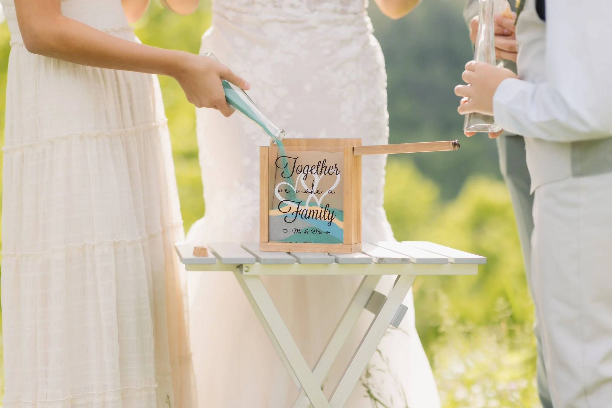 Family members pour colored sand into a keepsake box during a unity ceremony, a meaningful detail documented by a Gatlinburg wedding photographer.