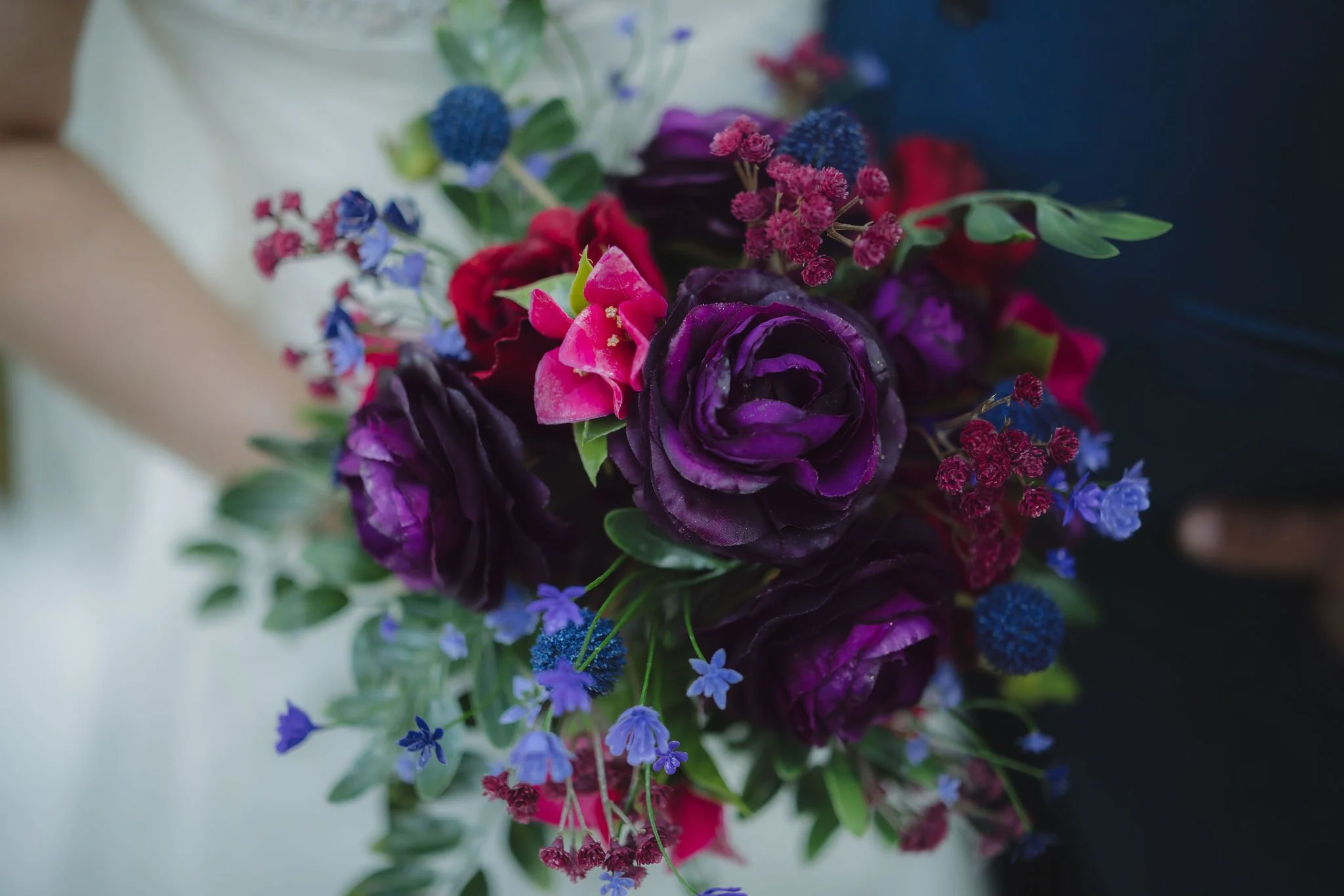 Detailed photograph of a bold wedding bouquet featuring deep purple roses, magenta blooms, blue wildflowers, and greenery for a colorful Gatlinburg elopement.