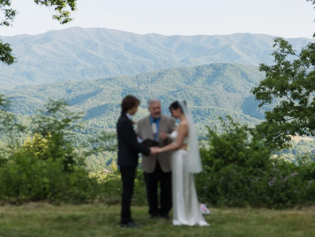 Wide view of an intimate wedding ceremony framed by trees and layered Smoky Mountain foothills, highlighting the mountain scenery found along Gatlinburg scenic drives.