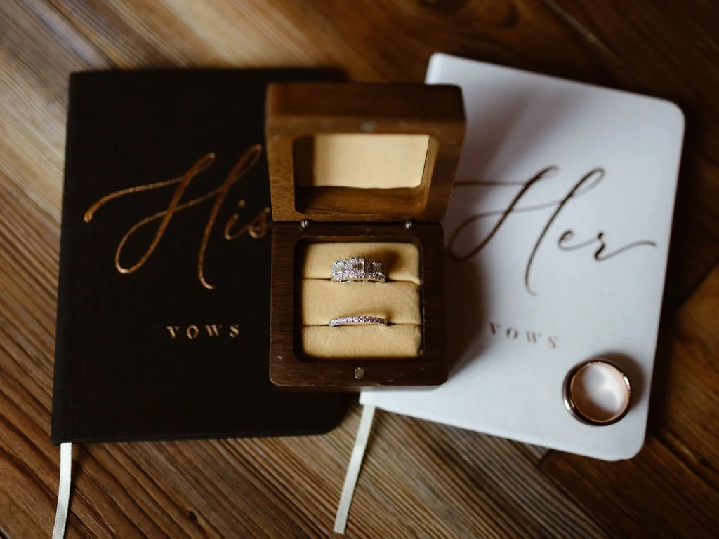 Wedding rings displayed in a wooden ring box beside personalized vow books during an intimate ceremony at Gatlinburg wedding cabins, detailed by an elopement photographer.