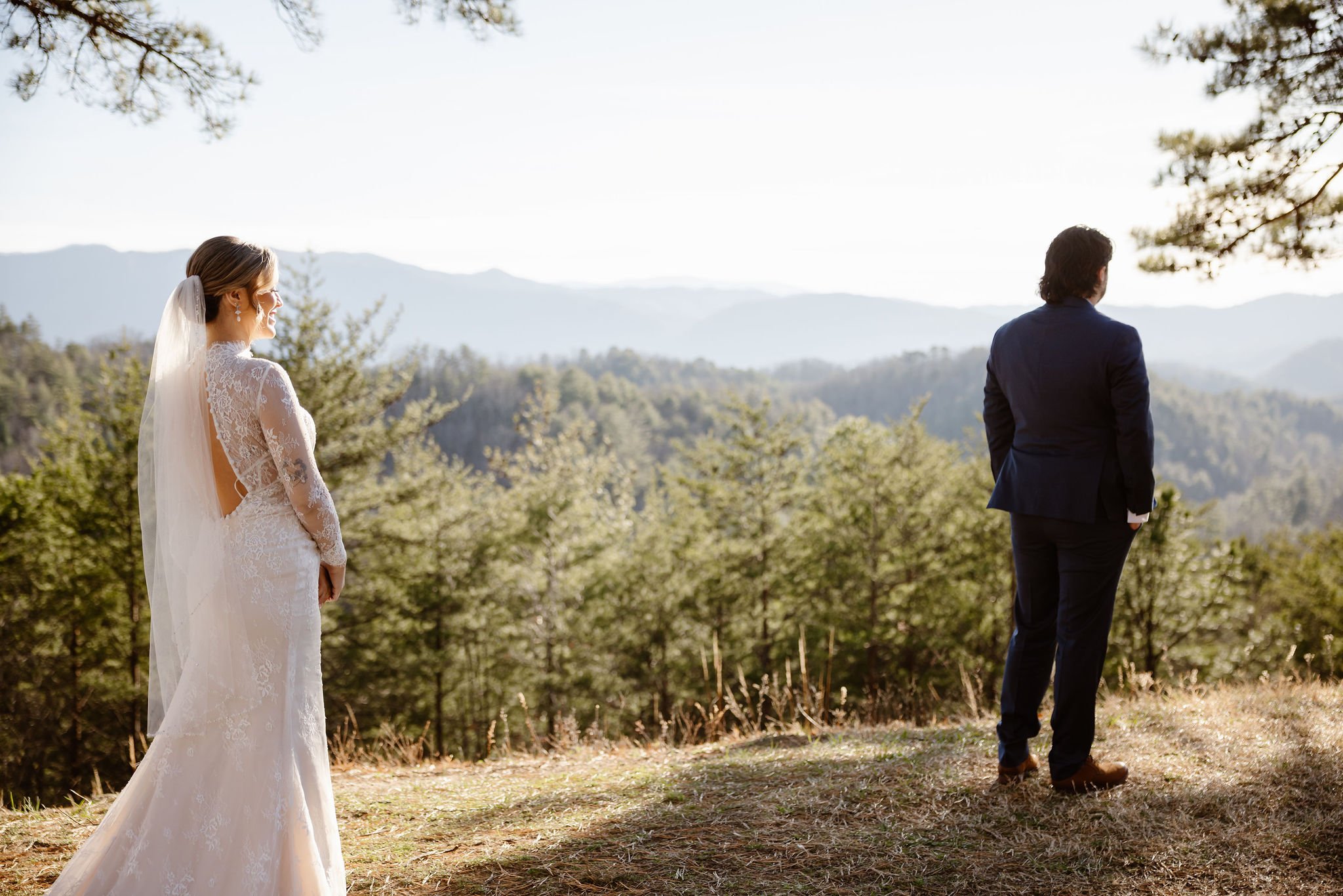 Bride and groom standing apart on a grassy overlook with scenic mountain views in the background at Foothills Parkway, captured by National Park Photographers in the Smoky Mountains.