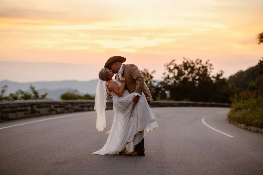 Sunset elopement at Foothills Parkway in the Smoky Mountains, with the groom dipping the bride in the middle of the scenic mountain road as golden hour light glows over the Appalachian ridgelines during a romantic Smoky Mountain elopement.
