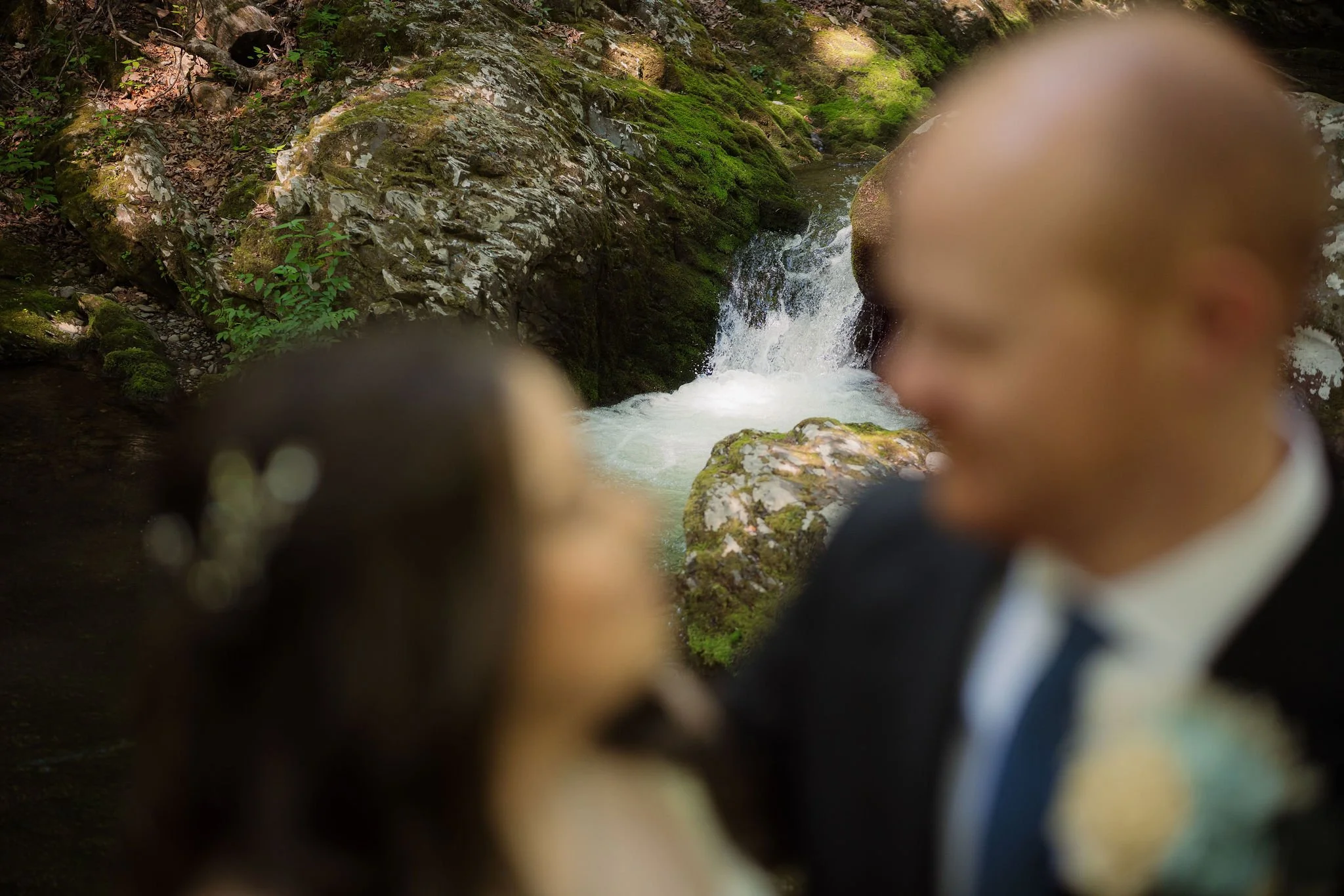 Bride and groom framed in soft focus beside a moss-covered waterfall in Greenbrier during their Smoky Mountains gatlinburg elopement.