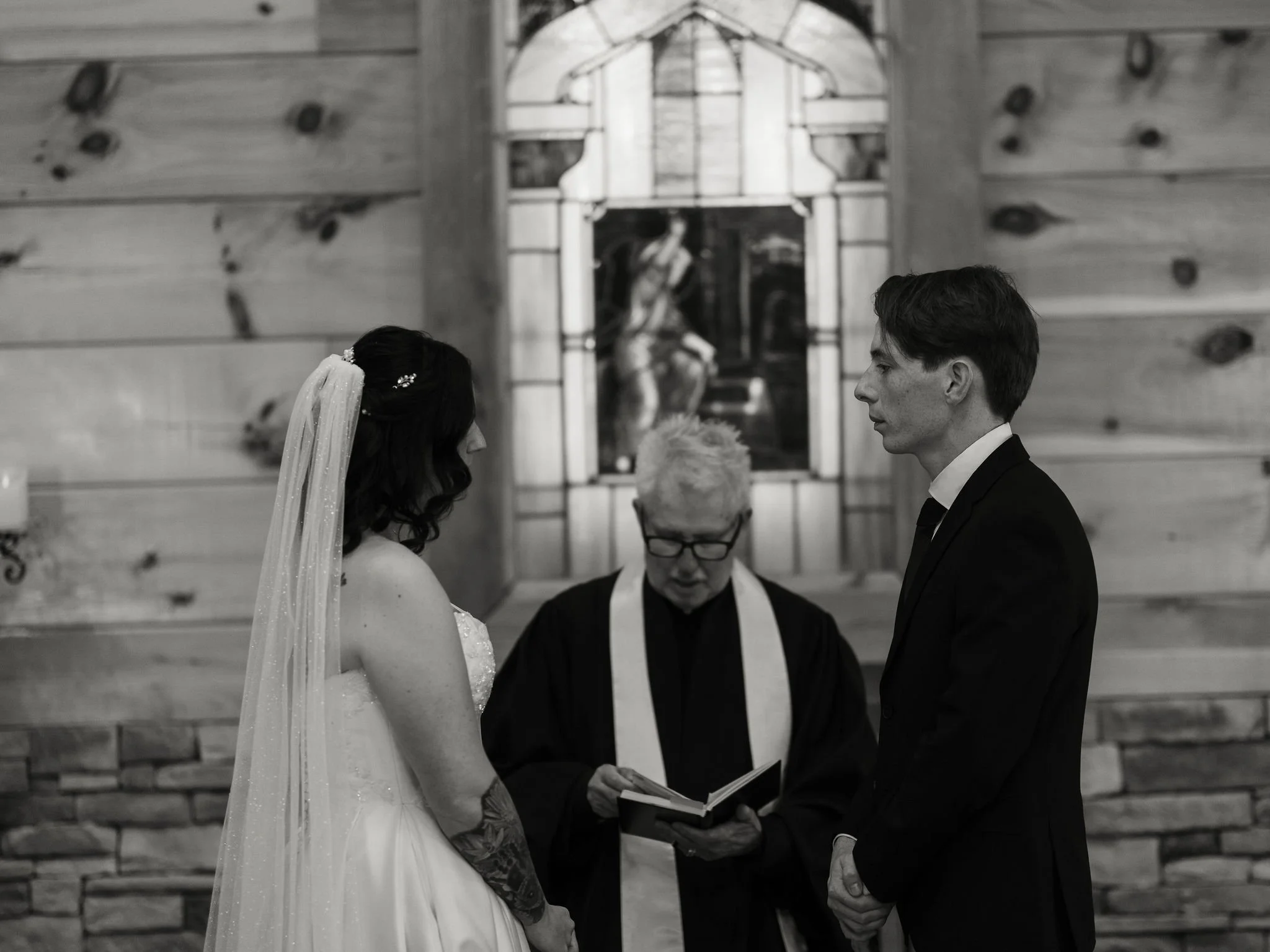 Black-and-white wedding ceremony as the couple faces each other before their officiant inside the rustic Little Log Chapel in Gatlinburg.