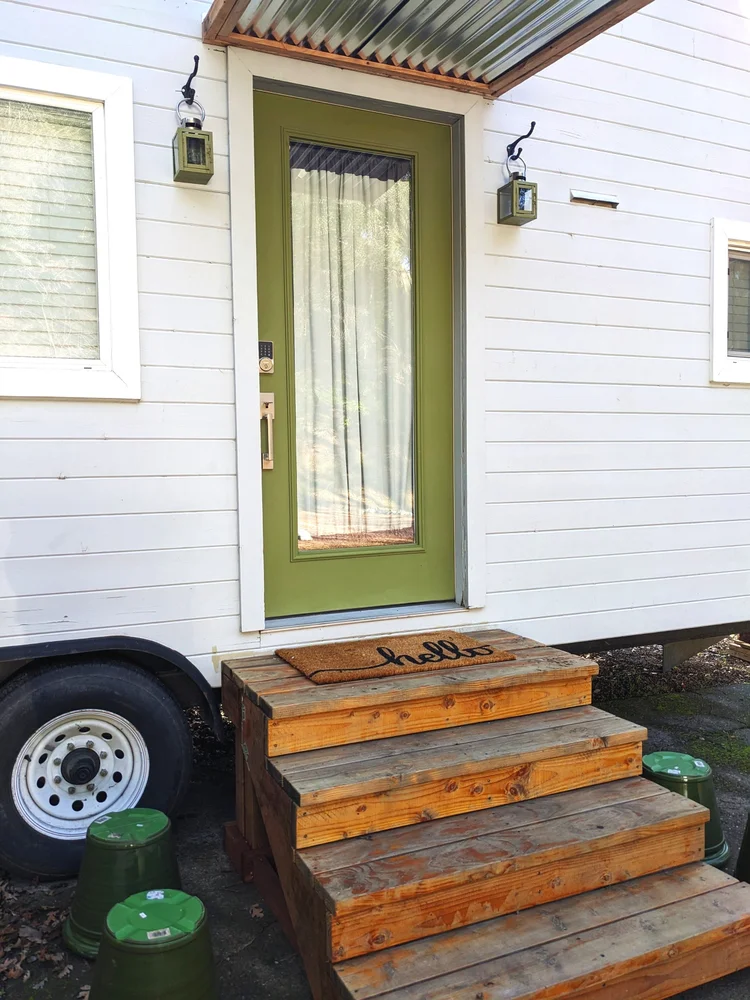 Tiny house entrance with green door and lanterns