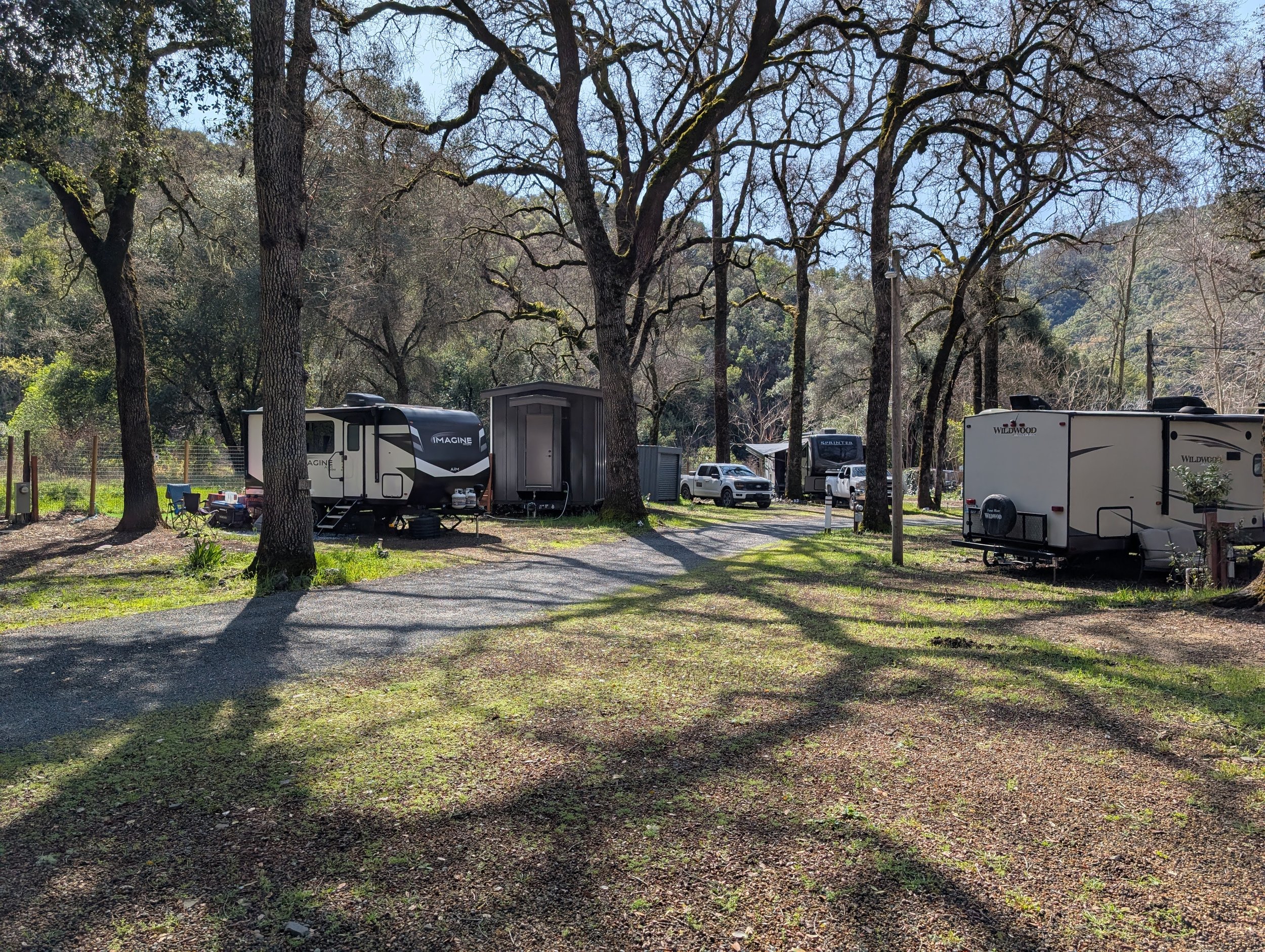 Campsite with RVs and a truck, surrounded by trees and natural landscape.