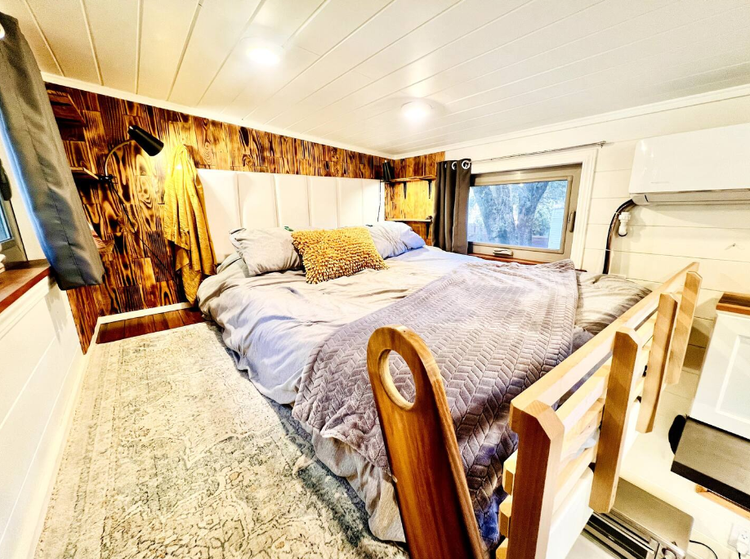 Cozy bedroom with a large bed, decorative pillows, and a wooden accent wall