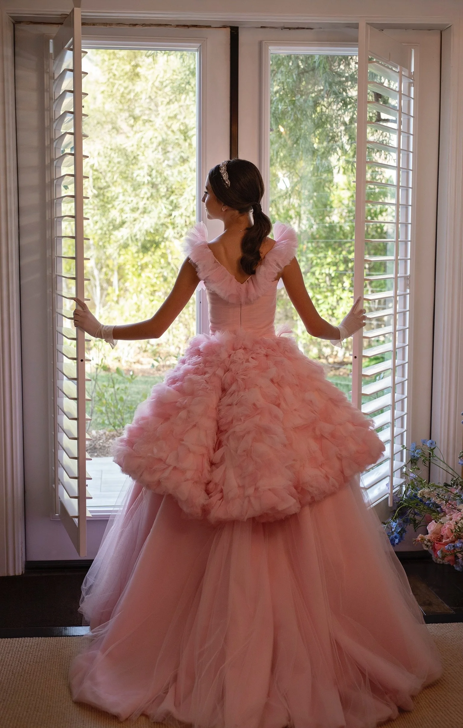 A modern couture quinceañera gown by RMINÉ, designed in layered pink and ivory tulle with a dramatic runway-worthy silhouette.