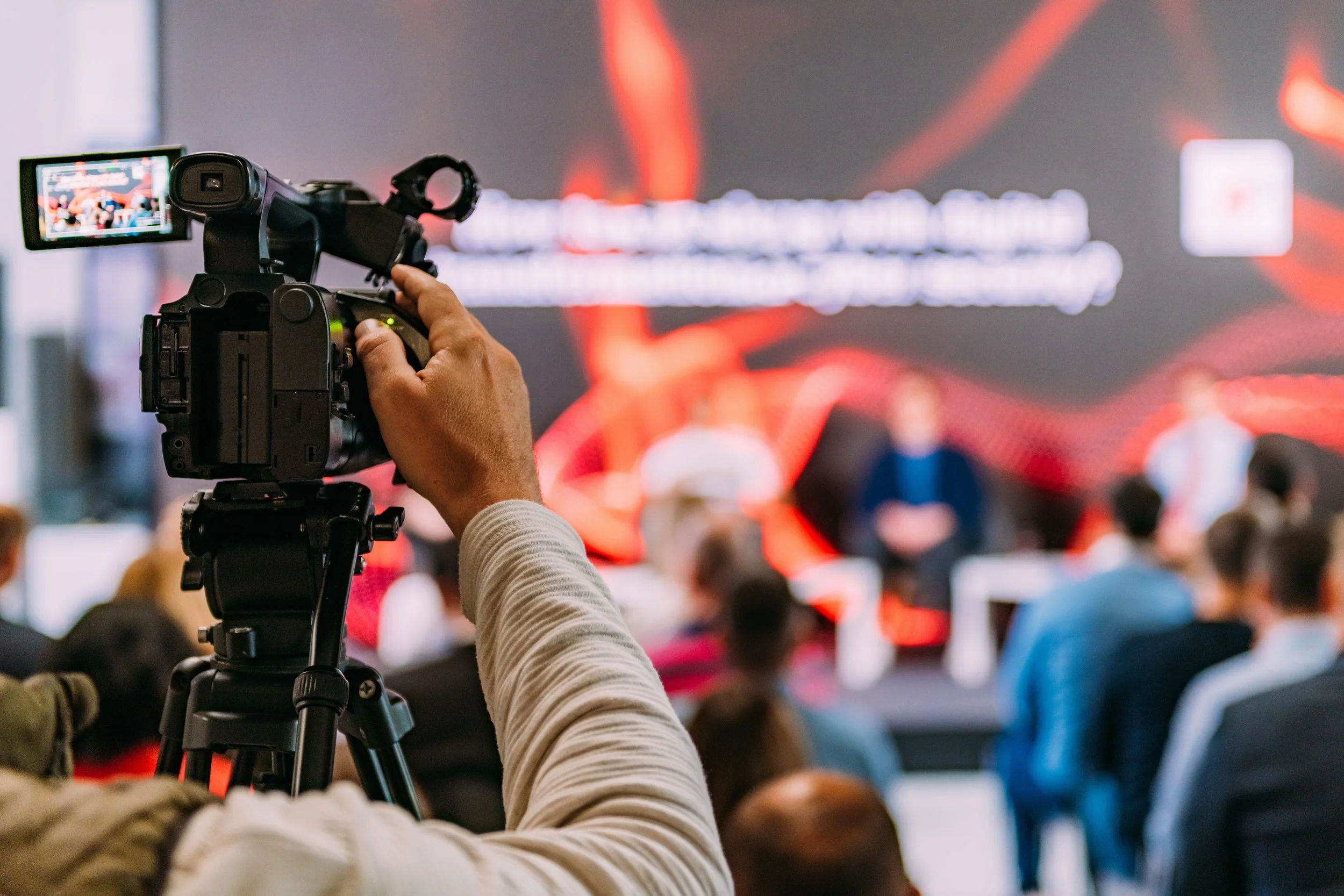 Videographer filming a corporate presentation and live stream event using a professional camera rig.