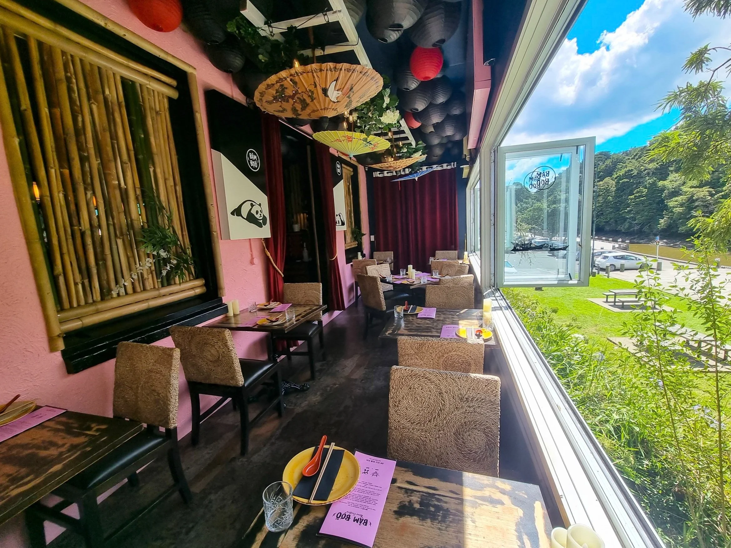 A dining room with eclectic decor and open windows which look out over the river.