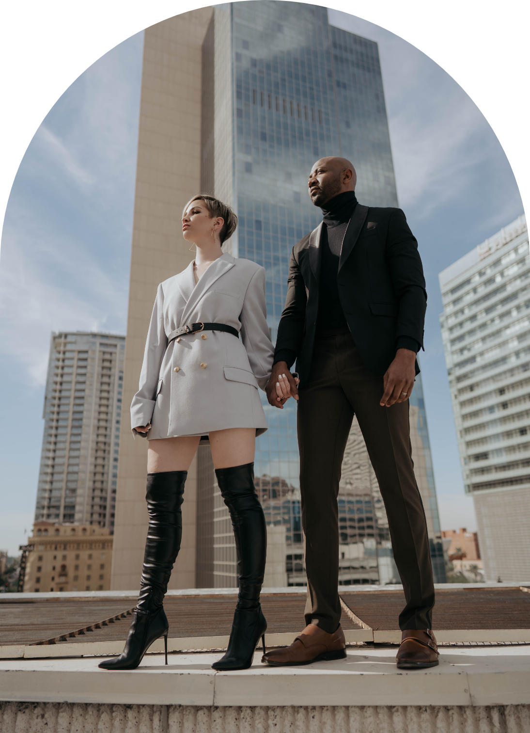 Alisha & Maurice Pennington, Small Business Coaches and Mentors hold hands in front of city background wearing professional business fashion