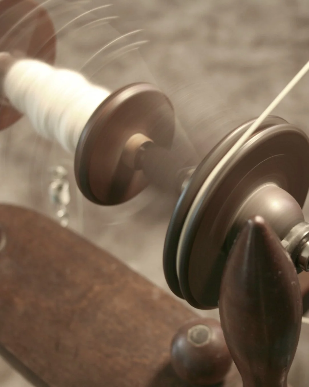 Close-up of a vintage spinning wheel bobbin, in motion creating blurred lines.