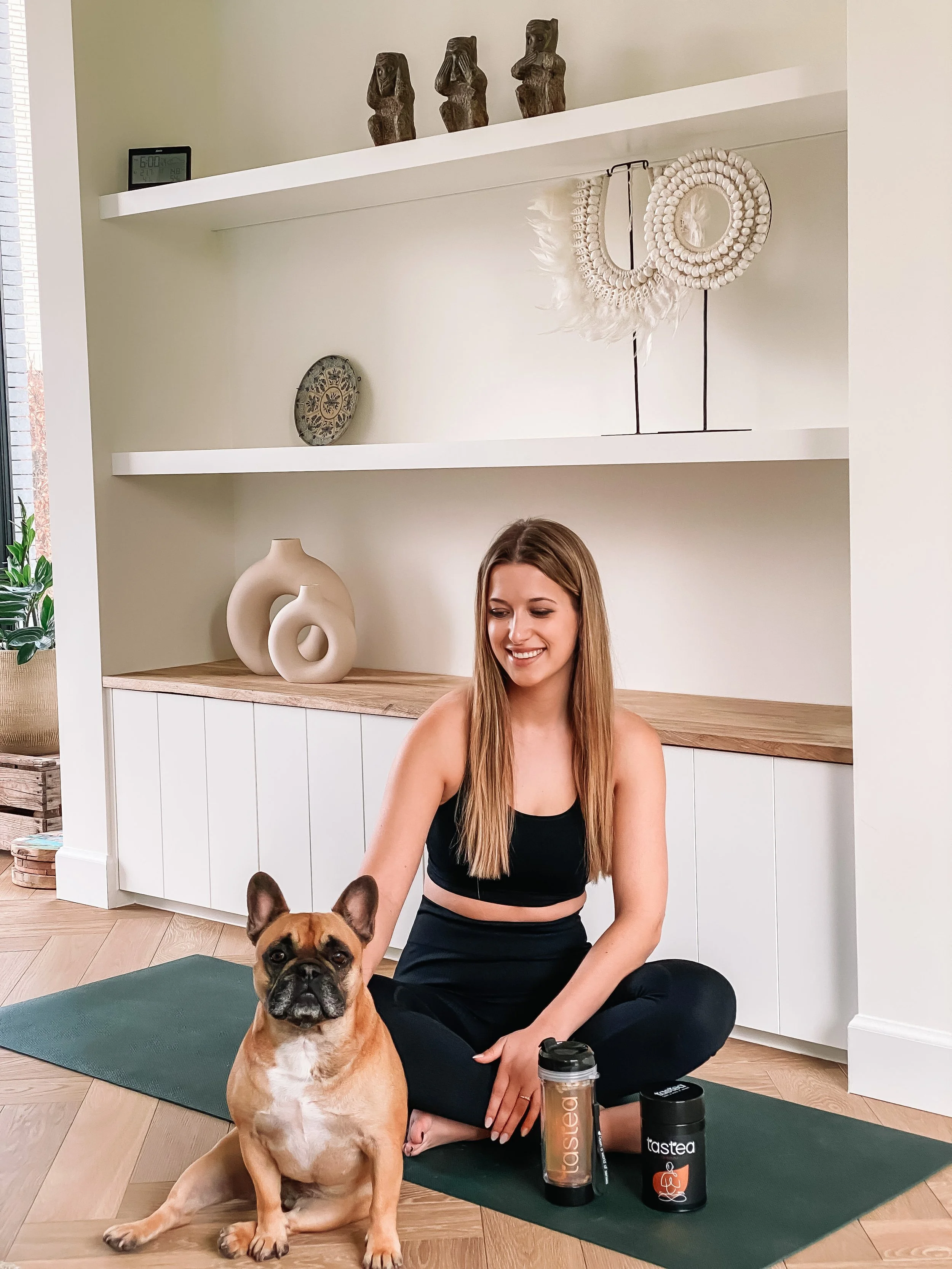 Vrouw zit op de grond met hond en theebeker