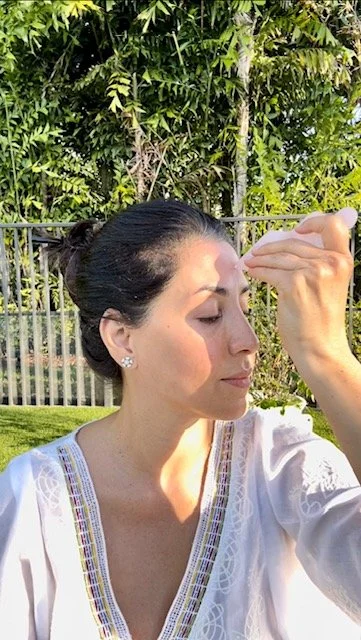 Woman using a facial roller and gua sha stone outdoors