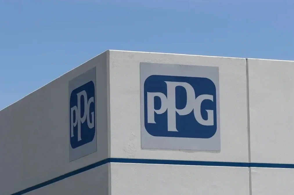 PPG logo on the side of a white building against a clear blue sky.