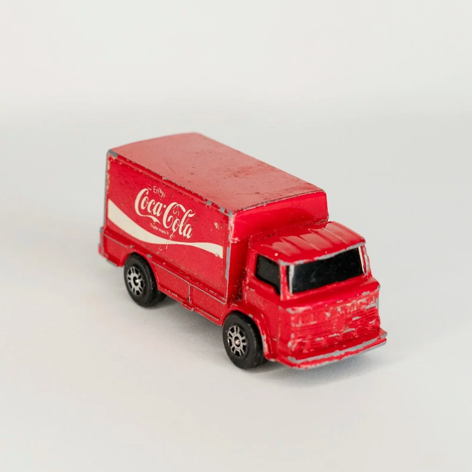 Miniature red Coca-Cola delivery truck toy on a white background.