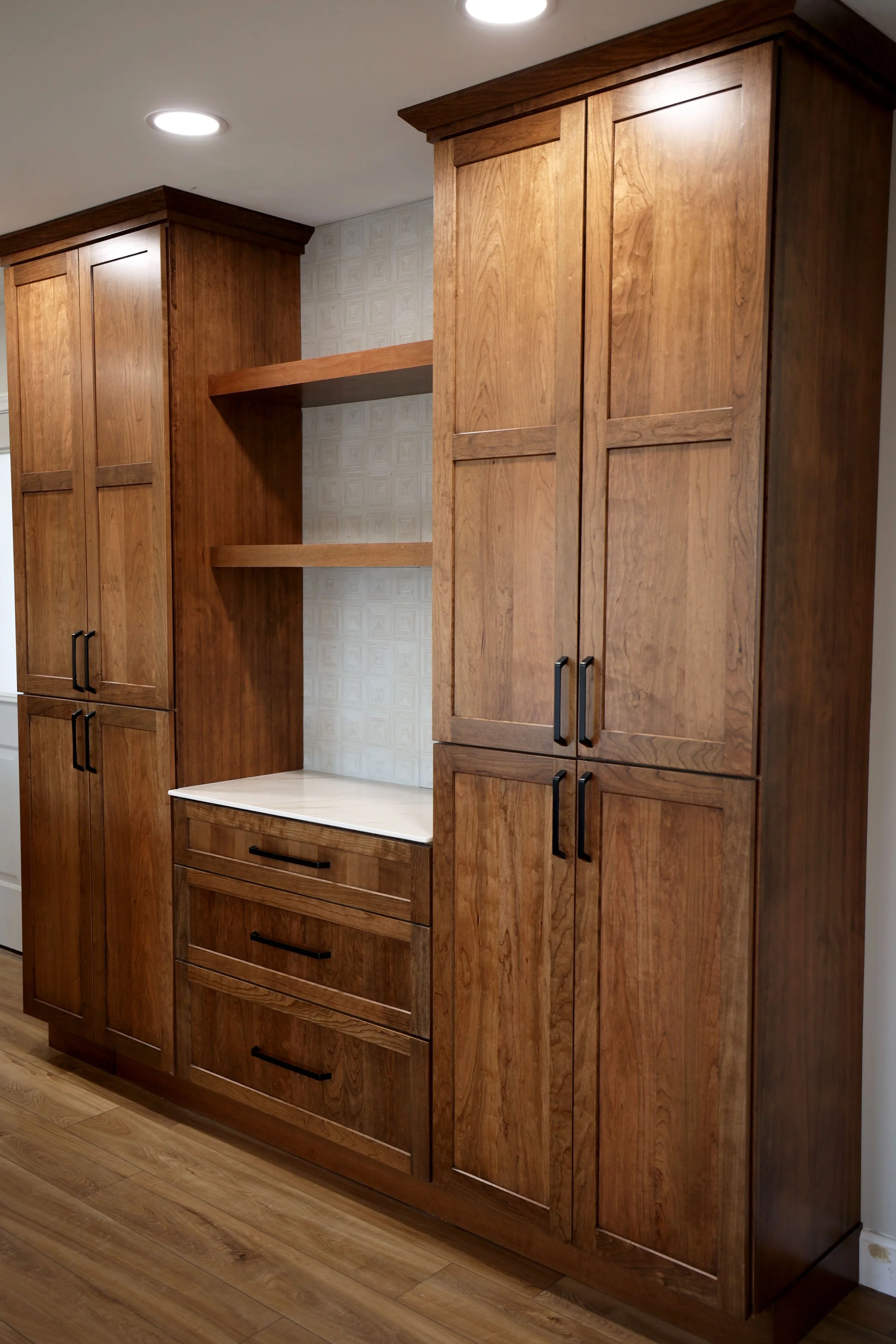 Wooden kitchen cabinets with black handles, open shelves, and drawers.