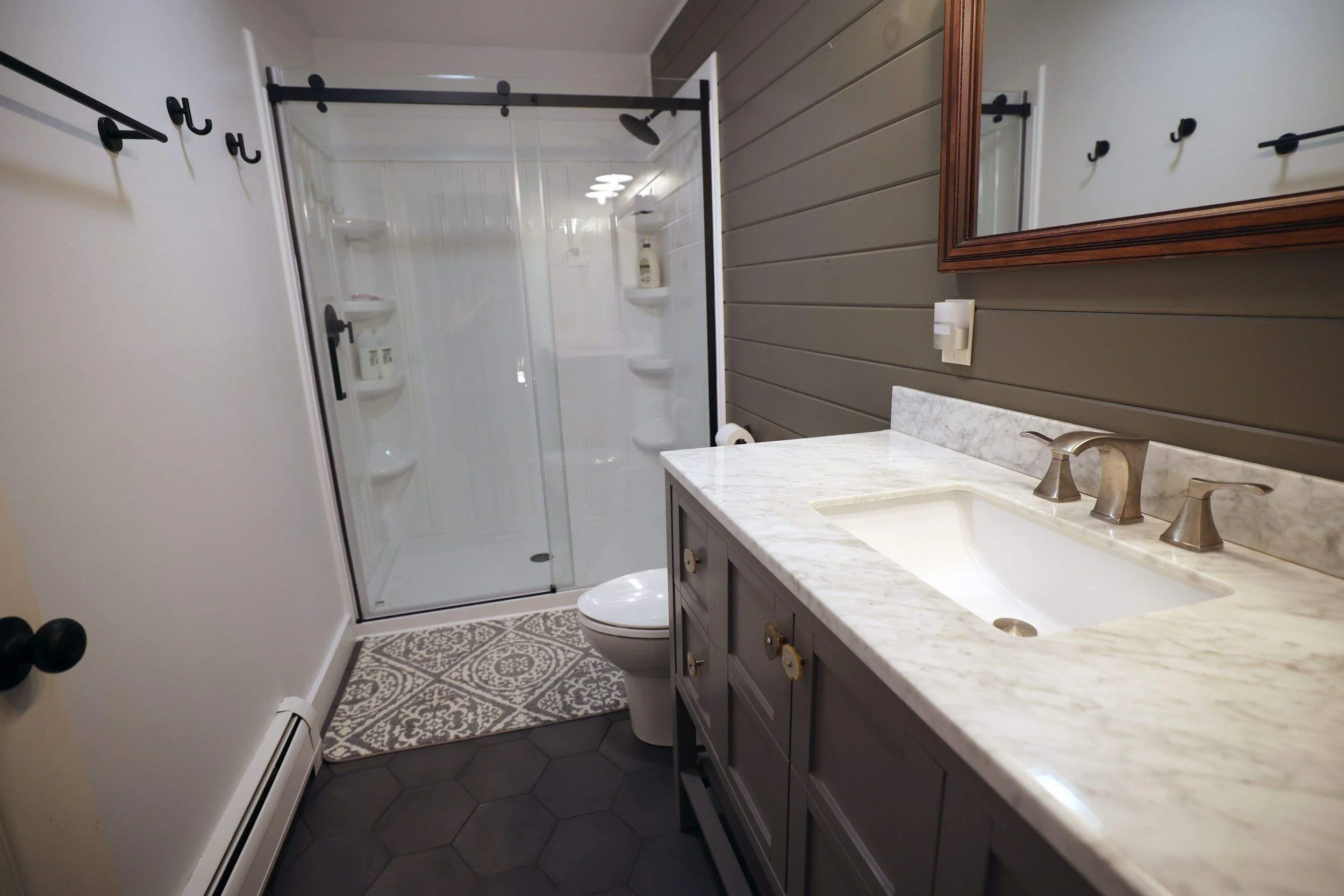 Bathroom with a shower stall, toilet, vanity with a marble countertop, and a mirror.