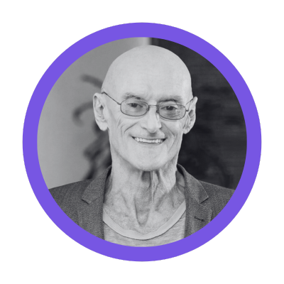 Smiling Ken Wilber wearing glasses and a suit jacket, framed in a purple circle.