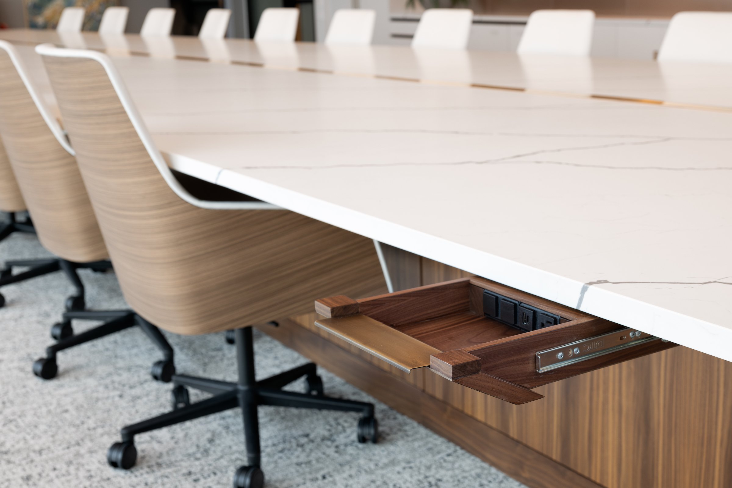 28 DRAWERS CONCEALED BENEATH THE QUARTZ TOP WITH BRONZE PULLS HOUSE TECHNOLOGY PORTS FOR EACH CHAIR