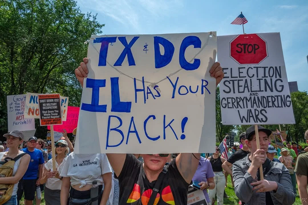 Rally to Stop Trump, August 2025 where protestors are supporting TX Dems who were in IL to stop gerrymandering there. Signs say TX DC IL Has Your Back and STOP Election Stealing and Gerrymandering Wars