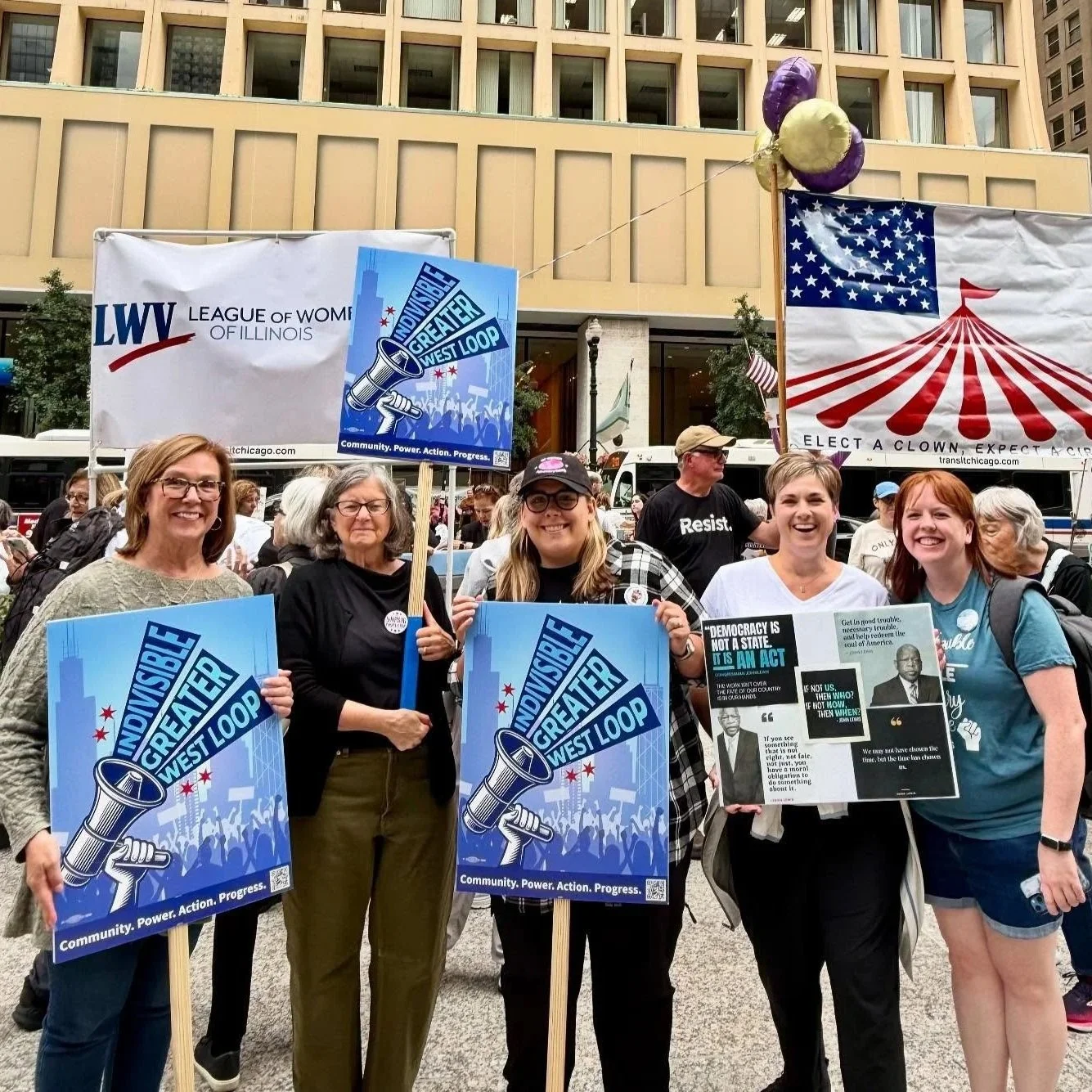 a group of volunteers holding signs at a rally that say Indivisible Chicago and Indivisible Greater West Loop.