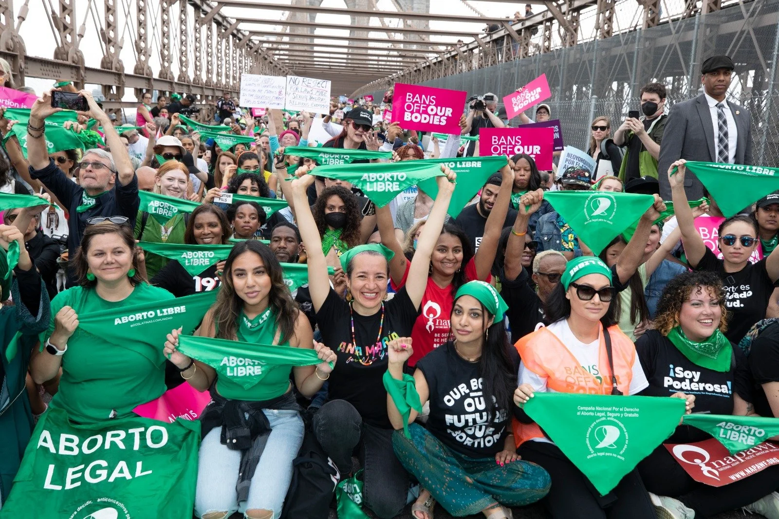Marchers kneeling on the Brooklyn Bridge, holding signs and banners