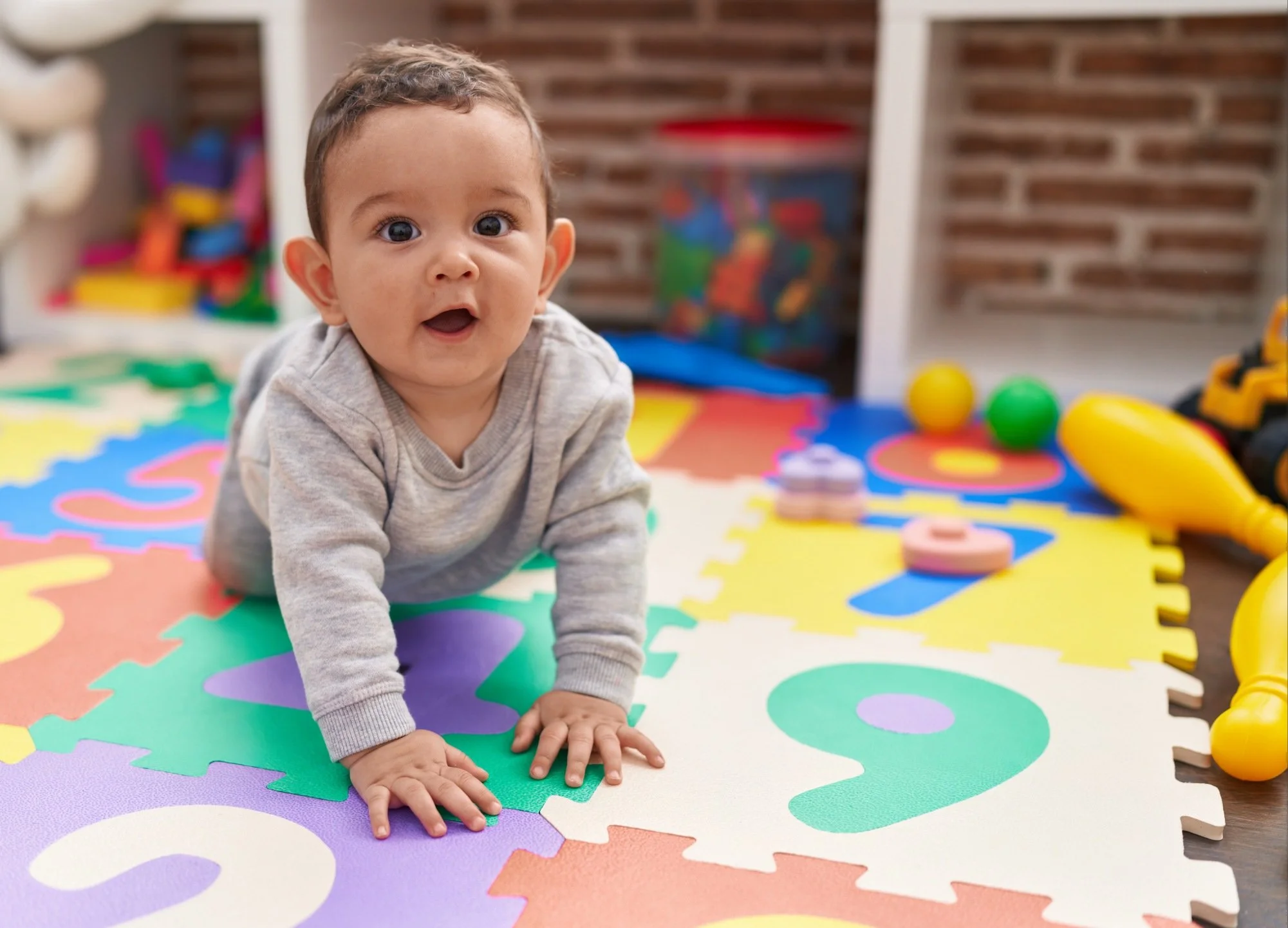 baby crawling on colorful mat during physical and developmental therapy with Buttonloop Children’s Therapies
