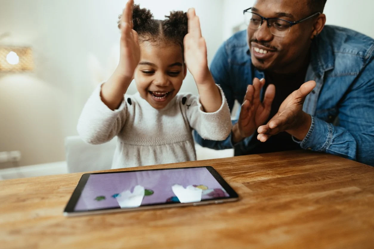 child and her dad during Speech Therapy for AAC (Alternative and Augmentative Communication) using an AAC device