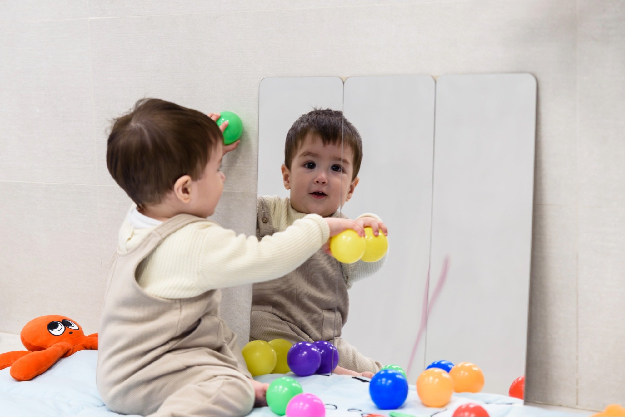 baby playing with balls in a mirror during speech therapy with Buttonloop Children’s Therapies infant services
