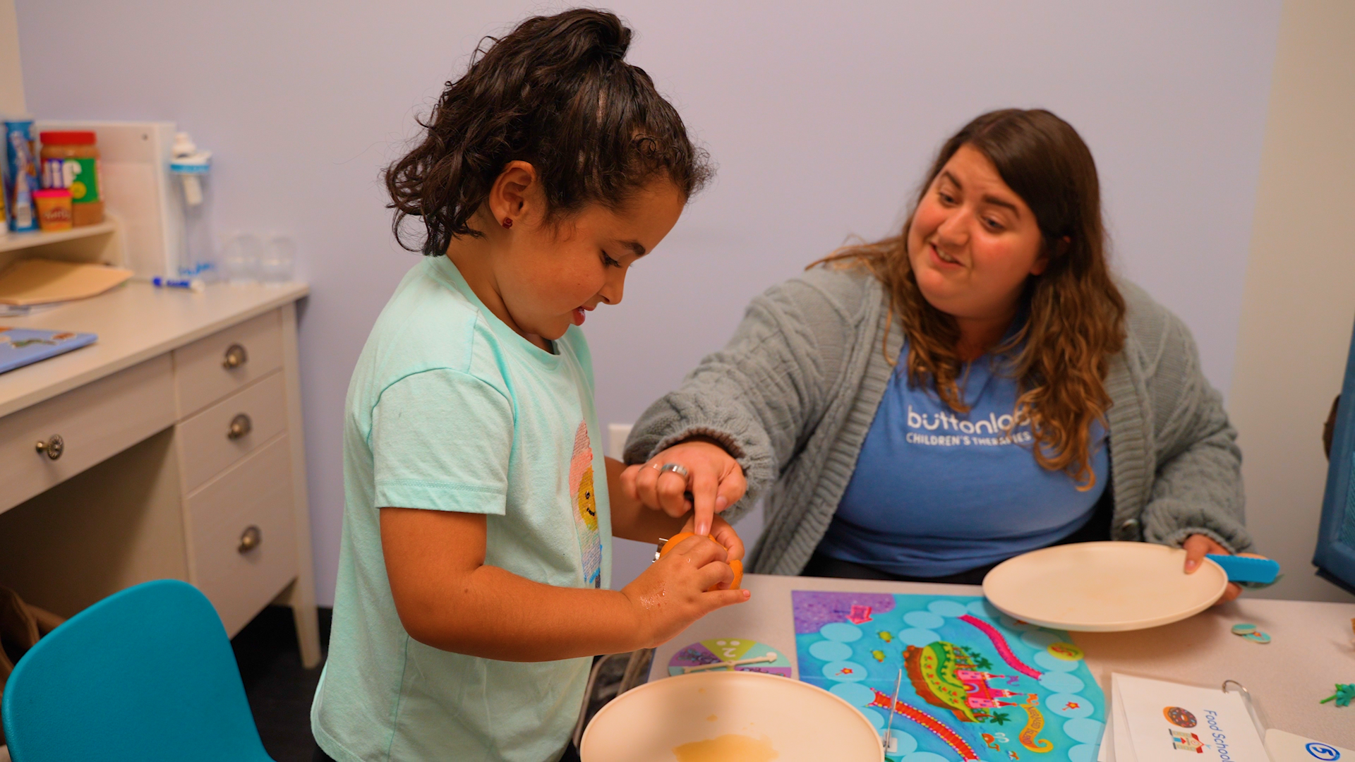 feeding therapist and child looking at a plate of food to eat