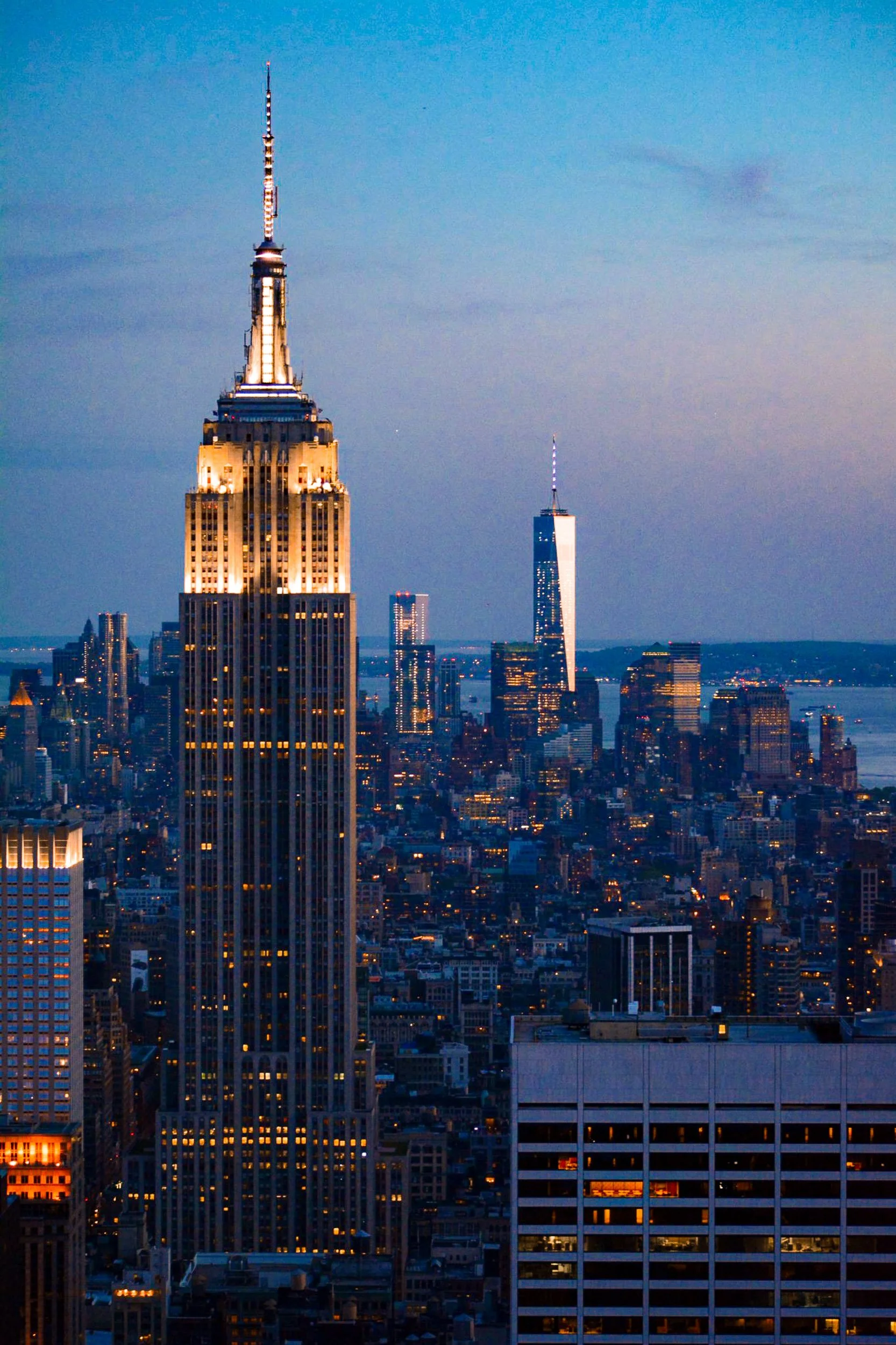 Empire State Building and Manhattan Skyline at Dusk - The illuminated spire of the Empire State Building stands as a central beacon amidst the glowing grid of Manhattan during twilight.