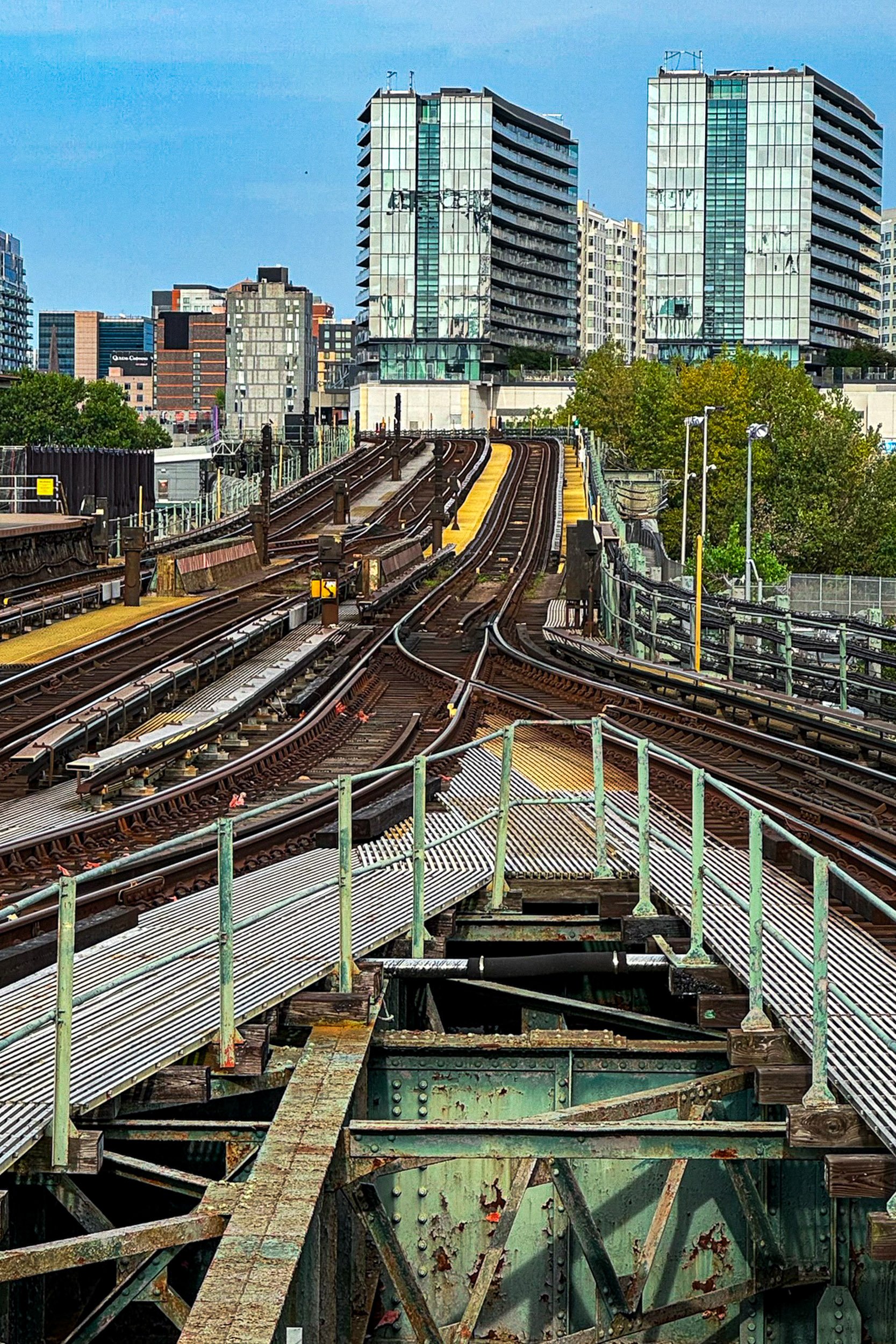 Elevated Transit Tracks - A stark, vertical look down the industrial steel framing and linear perspective of city transit tracks cutting through the architecture.