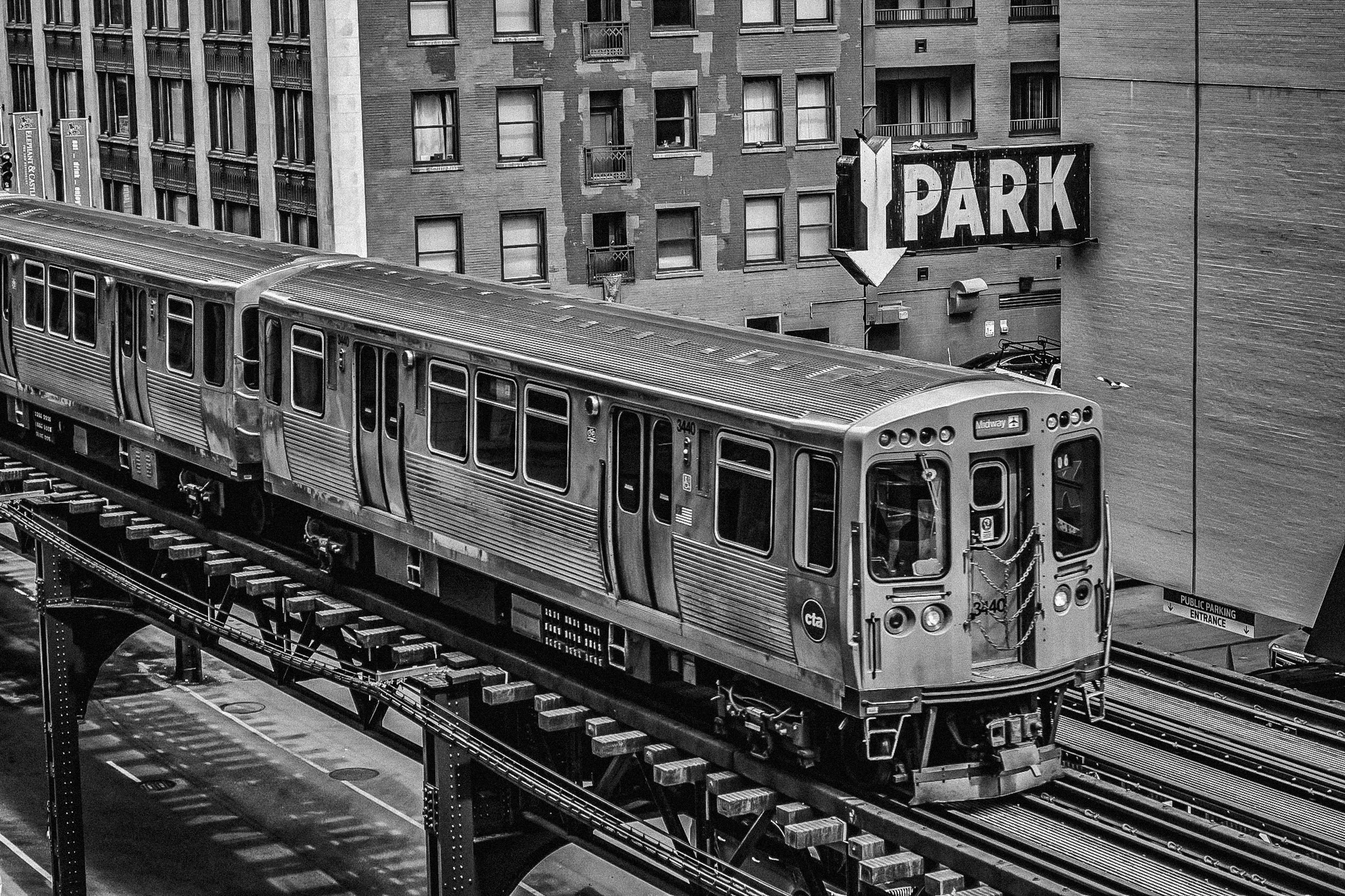 L-Train Frame - A classic Chicago street view framed beneath the heavy structural steel beams and tracks of the elevated L-train system.
