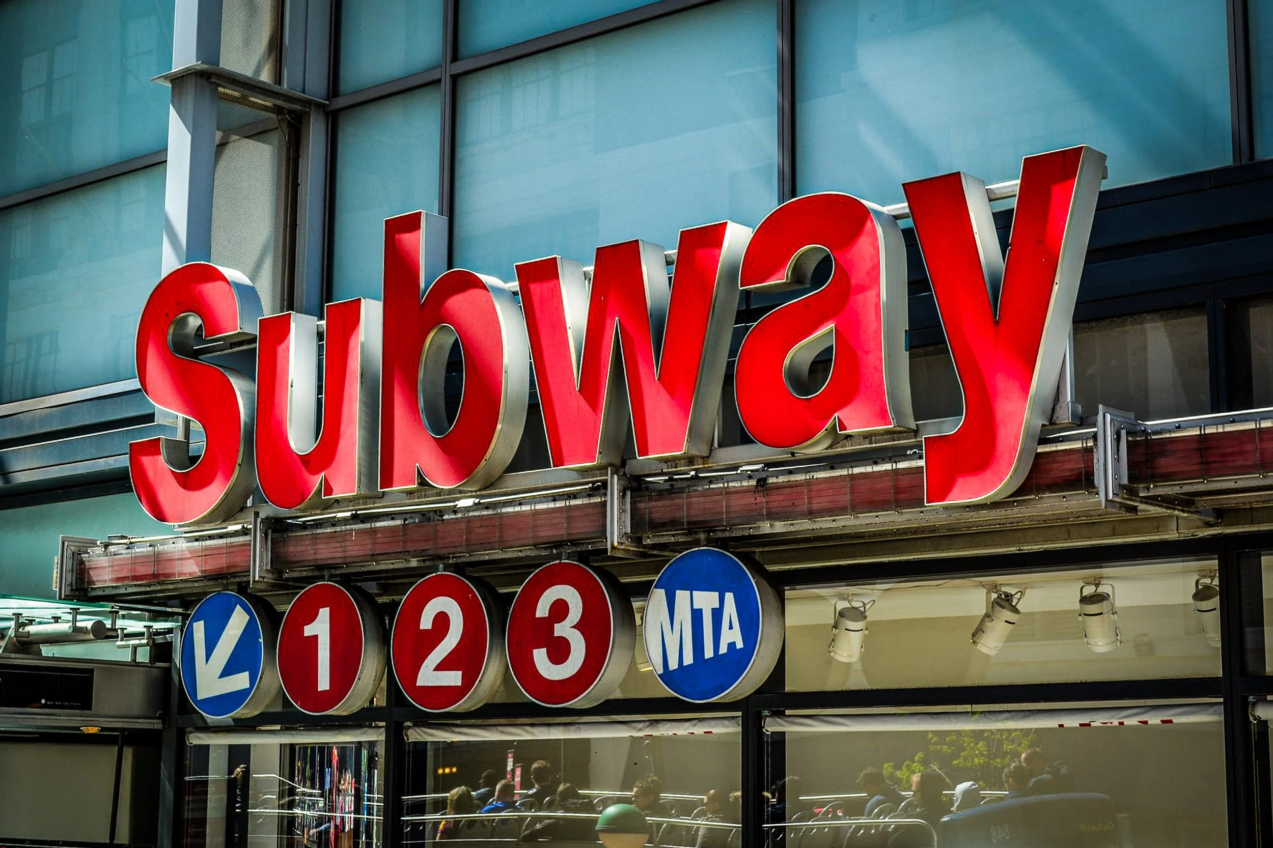Subway 1-2-3 Station Sign - A sharp graphic focus on the iconic numbered, colored circular discs of a New York City subway station entrance sign.