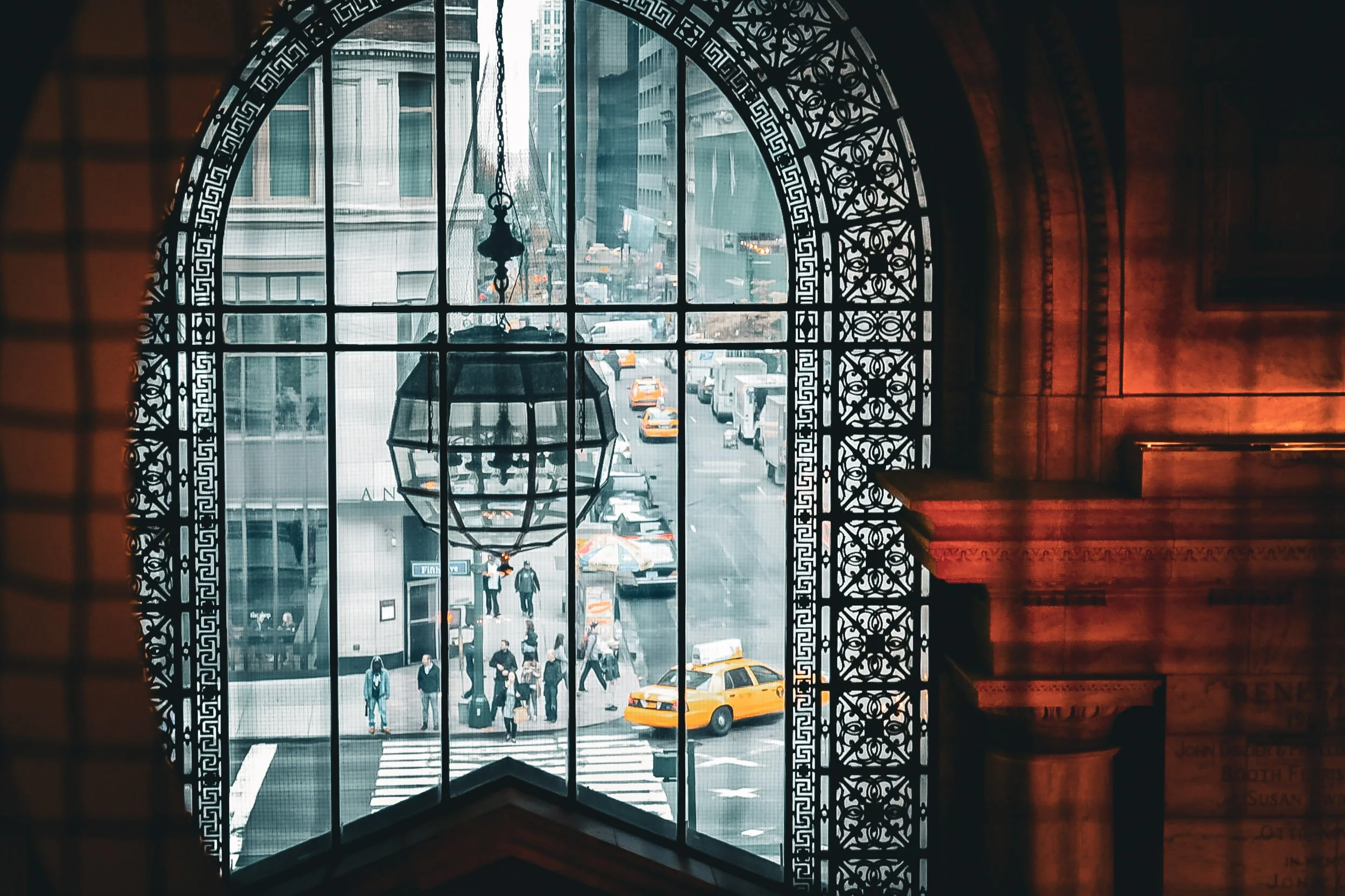 New York City Arched Window View - A dramatic architectural viewpoint looking out through a classic stone arched window, framing the dense layers of the New York skyline.